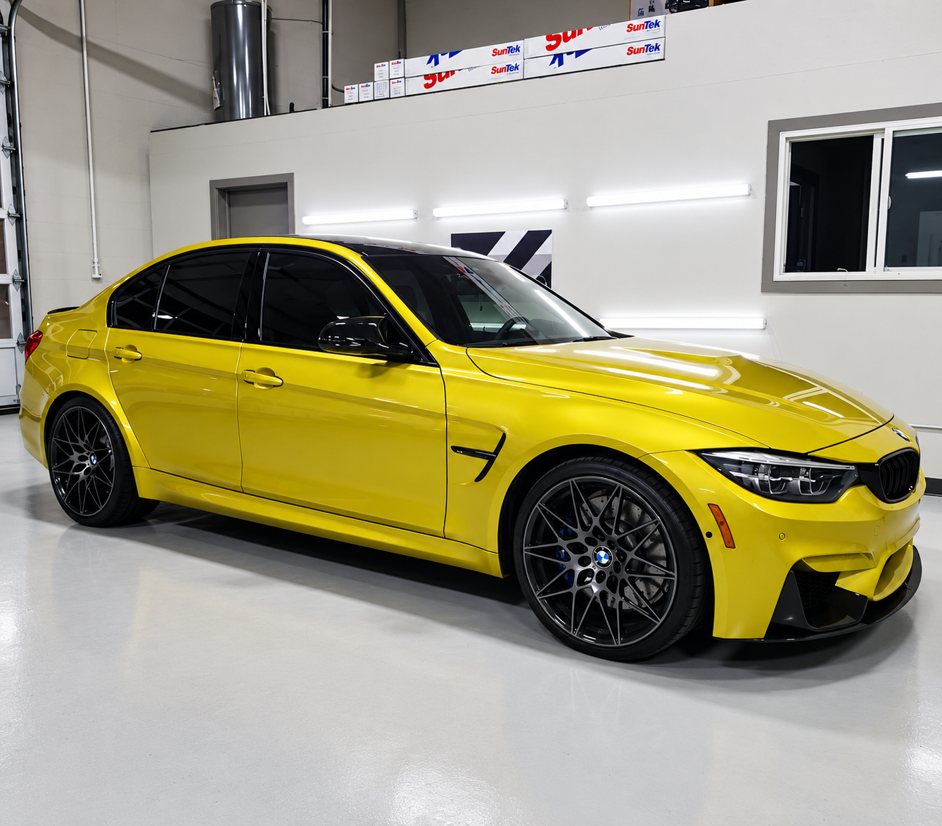 Yellow BMW with dark window tint inside the Tint X Calgary studio
